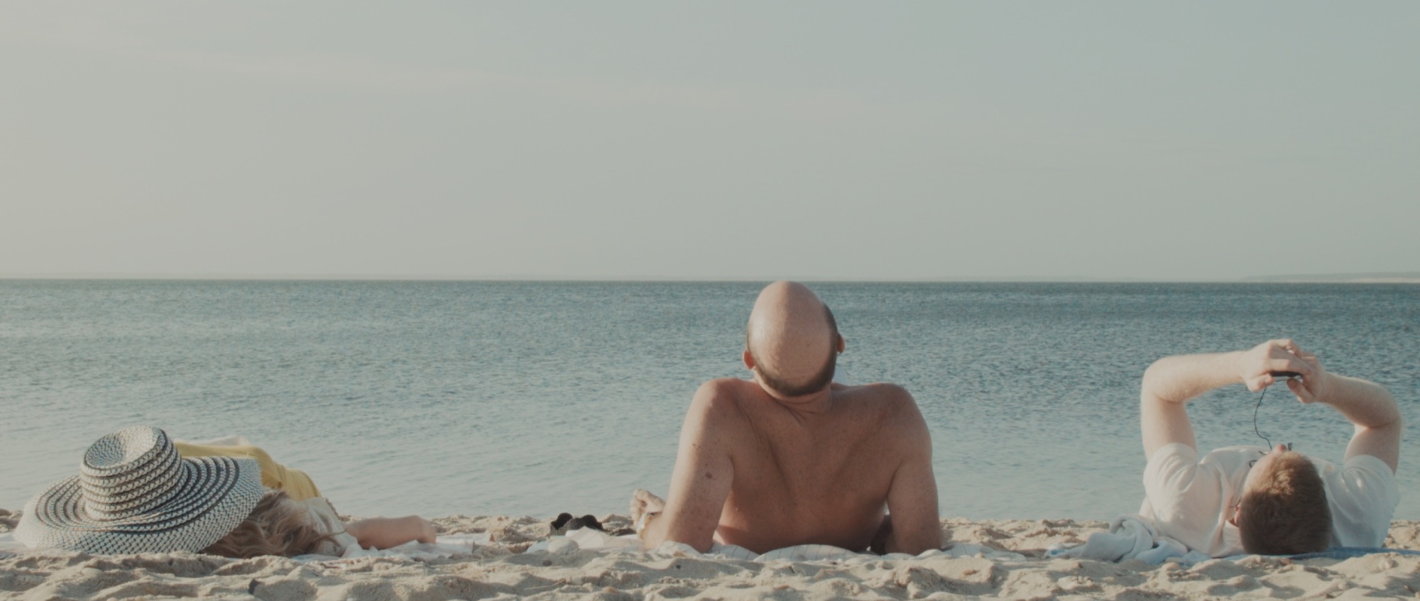 Cronos film still: three figures resting on the beach