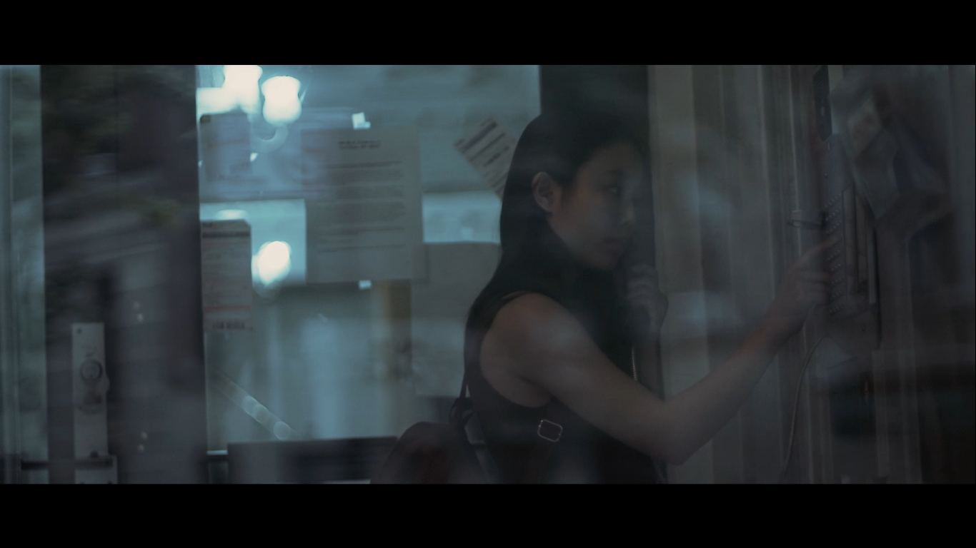 A woman using an apartment intercom behind glass