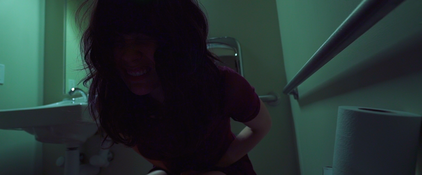 Sophia in a dim hotel bathroom
