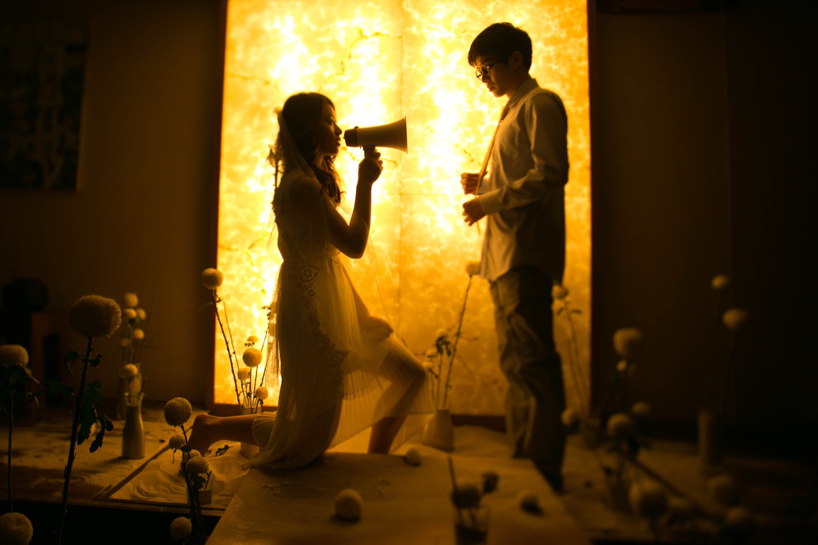 Starry Eyes still: a woman kneels with a megaphone before a glowing wall