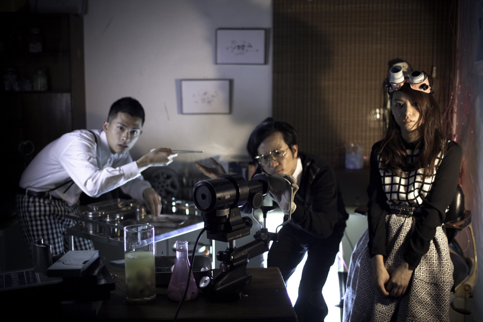 Starry Eyes still: three characters gather around an optical instrument